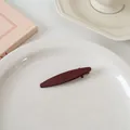Vue détaillée d'une pince à cheveux vintage en résine bordeaux sur une assiette blanche - Forme Ovale Étroite