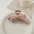Dettaglio di un mollettone a fiocco color malva lucido su un piatto bianco decorativo - Rosa