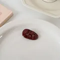 Détail de la pince à cheveux ondulée rouge bordeaux brillant sur plateau céramique - Goutte d'eau épaisse ondulée