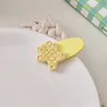 Close-up of a yellow checkered bear hair clip with HIME lettering on a white ceramic plate - Light Yellow