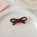 Gros plan d'une pince à cheveux nœud bordeaux brillant sur une assiette blanche - Thick Butterfly Knot