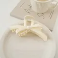 Dettaglio di una pinza per capelli a fiocco color panna in resina lucida su un piatto bianco - Bianco Lucido