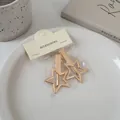 Zwei goldene sternförmige Metall-Haarspangen auf einer cremefarbenen Keramikplatte - Pentagramm Stern Stil (24#)