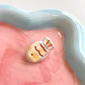 Detailansicht der 3D gelben Fisch-Haarklammer mit lila Karomuster auf einem Wellentablett - Gelb Kariert