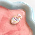 Macro detail of a striped macaron-colored resin fish hair clip on a pink ceramic plate - Colorful Twill