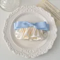 Detail von hellblauer Satinschleife Haarspange mit creme gefalteter Schleife auf Teller - Blau
