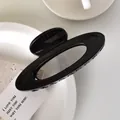 Macro shot of glossy black oval hollow hair claw clip on minimalist stone surface - Glossy Black