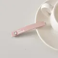 Détail d'une pince à cheveux rose avec strass en cœur et texte sur soucoupe en céramique - Rose