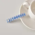 Détail d'une barrette à carreaux bleus avec strass en cœur et lettrage sur la table - Plaid Bleu
