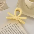 Gros plan d'une pince à cheveux nœud jaune crème au fini mat sur un bureau épuré - Nœud / 9cm / Jaune Lait