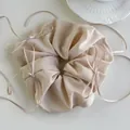 Macro detail of a beige satin oversized scrunchie with delicate silk ribbon bows - Milk Coffee