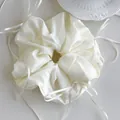 Detail of cream white oversized scrunchie with romantic ribbon ties and pleated texture - White
