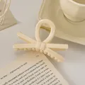 Gros plan d'une pince à cheveux nœud crème posée sur un livre ouvert sous une lumière douce - Nœud / 9cm / Beige