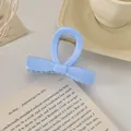 Gros plan d'une pince à cheveux nœud bleu clair posée sur un livre ouvert avec style - Décoration de Nœud / 8cm / Bleu Lait