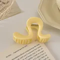 Détail d'une pince à cheveux jaune crème ondulée avec finition brillante et ressort doré - Pince en S / 8cm / Jaune Lait