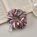 Detail der Textur eines blau-rot gestreiften Strick-Scrunchies mit FMdrea-Etikett - Blau Rot Gestreift - Regulär