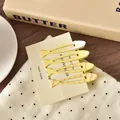 Detailaufnahme von vier süßen fischförmigen Haarspangen in Gelb- und Pastelltönen - Gelber Fisch Stil