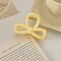 Détail de la pince à cheveux nœud jaune crème montrant la texture résine et le ressort - Nœud Évidé / 8cm / Jaune Lait