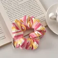 Detail view of pink and yellow striped fabric scrunchie resting on an open book - Pink Yellow Striped - Regular