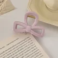 Détail de la pince à cheveux rose en forme de nœud avec ressort doré sur un livre - Nœud Évidé / 8cm / Rose Poudré
