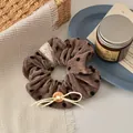 Detail of vintage velvet polka dot scrunchie with lace edge and wooden button decoration - Coffee