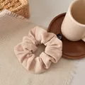 Detail of a large beige velvet scrunchie with fine texture and black flower logo tag - Off White