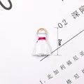 Detailed view of a 2cm white mini tassel charm with gold ring for DIY jewelry making - White