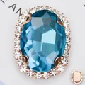 Nahaufnahme von ovalem blauem Glasstein mit roségoldener Kupferfassung zum Nähen - Gold Seeblau Strass