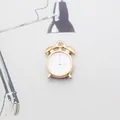Detailed close-up of a gold alloy alarm clock charm with white enamel dial finish - White