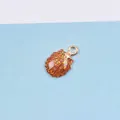 Detail eines muschelförmigen Anhängers mit goldener Basis und glitzerndem Öl-Finish - Kaffeebraun