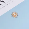 Makro-Detail des schneeflockenförmigen Goldanhängers mit Perle und glänzenden Strasssteinen - Perlenstil / Gold