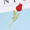 Detailed close-up of a golden tulip brooch with red crystals and a white pearl accent - Red