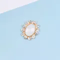 Detail of oval alloy decorative buckle with central stone and rhinestones on gold base - Jelly White