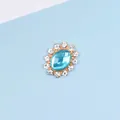 Macro detail of oval light blue gemstone accessory with white rhinestone halo in gold - Lake Blue