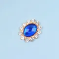 Detail of oval gold alloy buckle with blue diamond gemstone and white rhinestones - Sapphire Blue