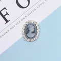 Close-up of vintage oval cameo button with white relief and crystal rhinestone border - Gray
