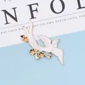 Macro detail of bird alloy brooch with white enamel oil drop and golden floral branch - Left Side White
