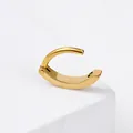 Polished golden stainless steel belly piercing ring on white stone display base - Gold