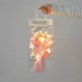 Rosa-weißer Trockenblumenstrauß mit LED-Lichtern in transparenter Geschenktüte - Rosa Nelke Stil