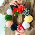 Detalle de guirnalda de bolas de lana de colores con lazo rojo para adornos navideños - Estilo Pequeño