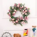 Pink and purple rose flower wreath with green leaves hanging on a white wall - Camellia Leaf Wreath