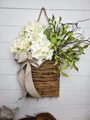 Close-up of artificial white hydrangea and green leaves in rustic rattan door basket - Green