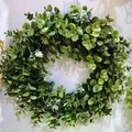 Detailed view of artificial greenery wreath with white flowers on a white wall - Style H