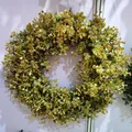 Detailed close-up of lush artificial boxwood leaf wreath on a white wall - Style G