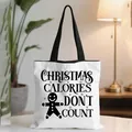 White Christmas tote bag with gingerbread print and black handles on a desk - White Slogan Gingerbread Man (02)
