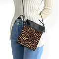 Crossbody bag with leopard pattern and black trim worn by a model in casual outfit - Brown and Yellow Zebra Print