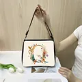 Close-up of floral letter Q print on minimalist beige canvas tote bag with black strap - Q17 (Letter Q)