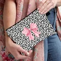 Leopard print makeup bag with pink ribbon bow held by a person in a casual setting - Black and White Leopard Large Pink Bow Style (03)