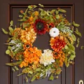 Gros plan détaillé d'une couronne d'automne avec tournesols, baies et citrouille sur porte - Tournesol Rouge Foncé et Baie Orange (B025)
