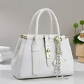 Close-up of white embossed leather handbag with golden metal buckle and stripe knot decor - Off White